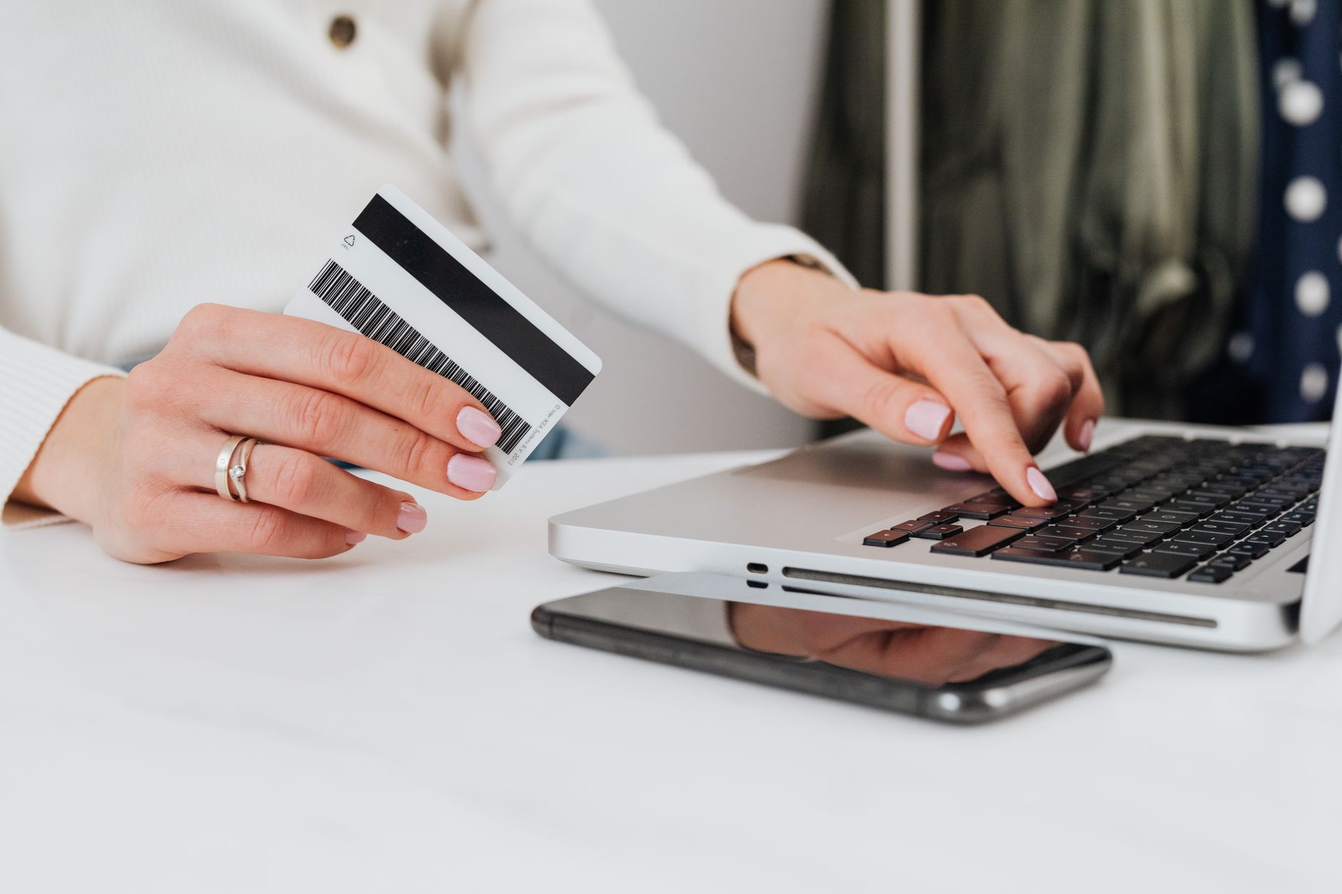 a person holding a credit card and looking at a smartphone at a desk