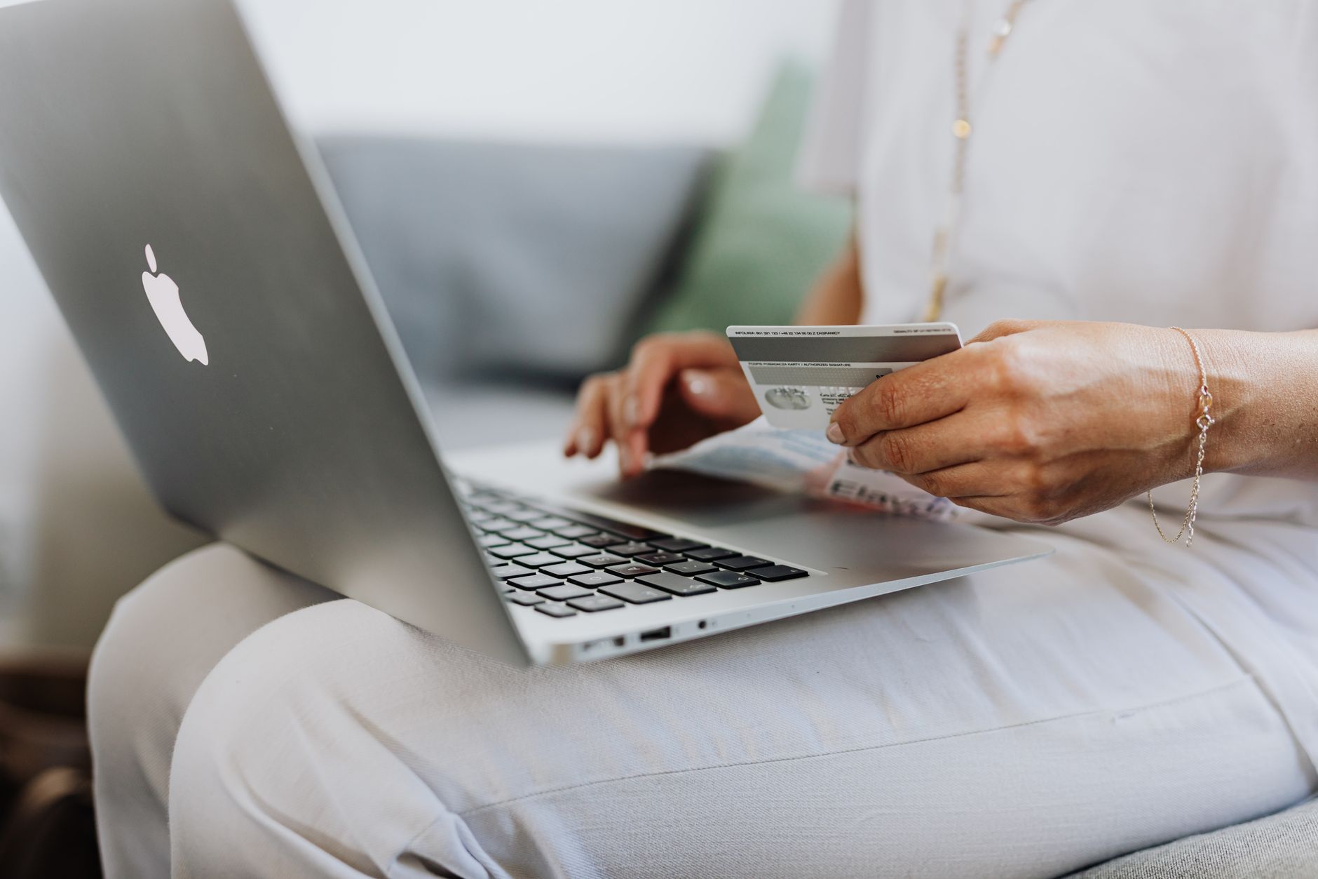 a person holding a phone to one ear and a credit card in the other hand at a table