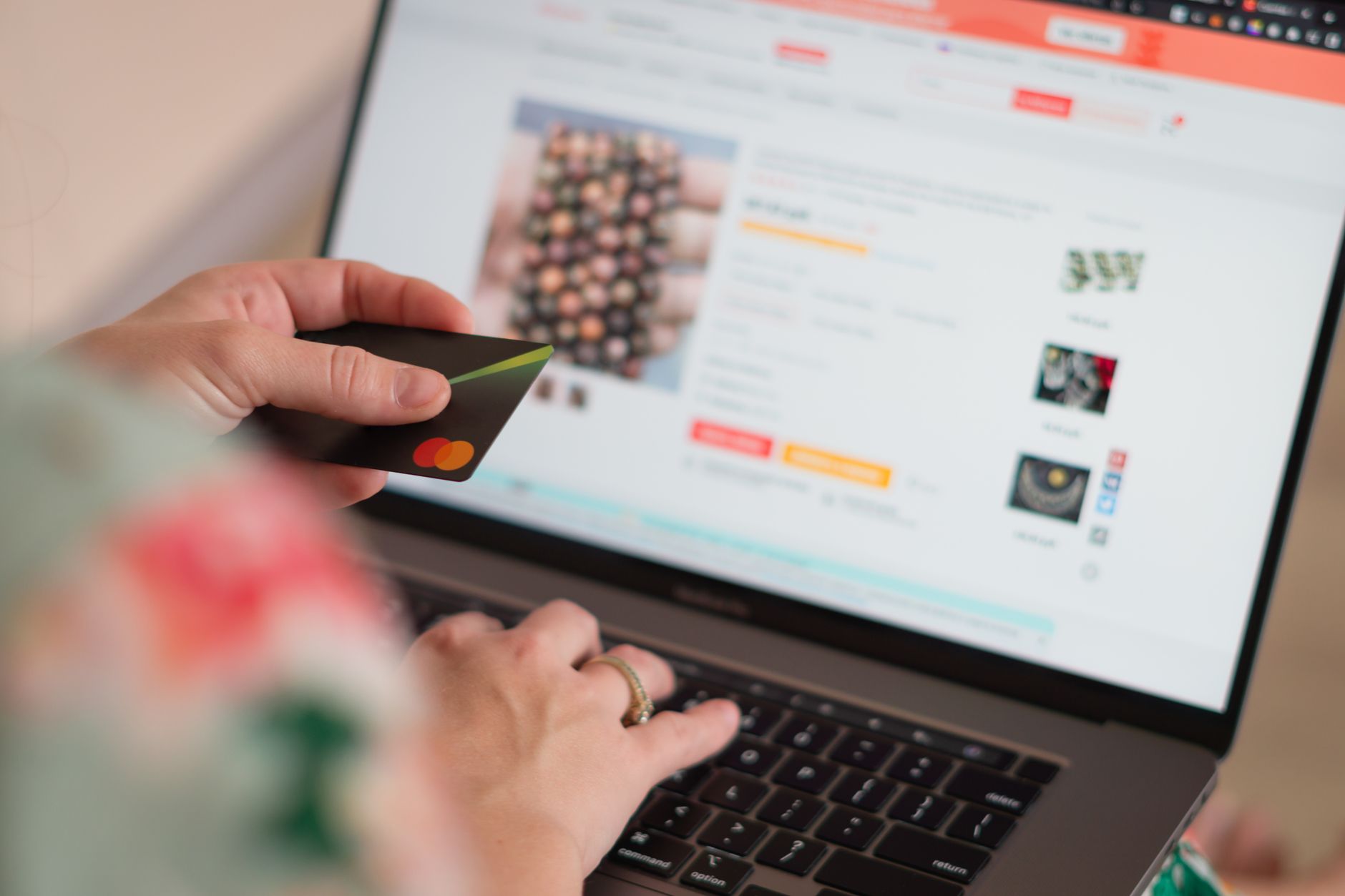 a person typing a search query on a laptop while a credit card sits next to the keyboard