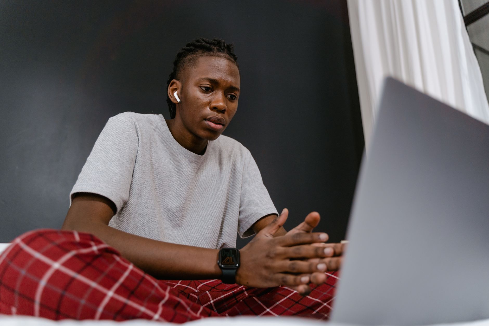 a person watching a video call on a laptop with a doubtful look