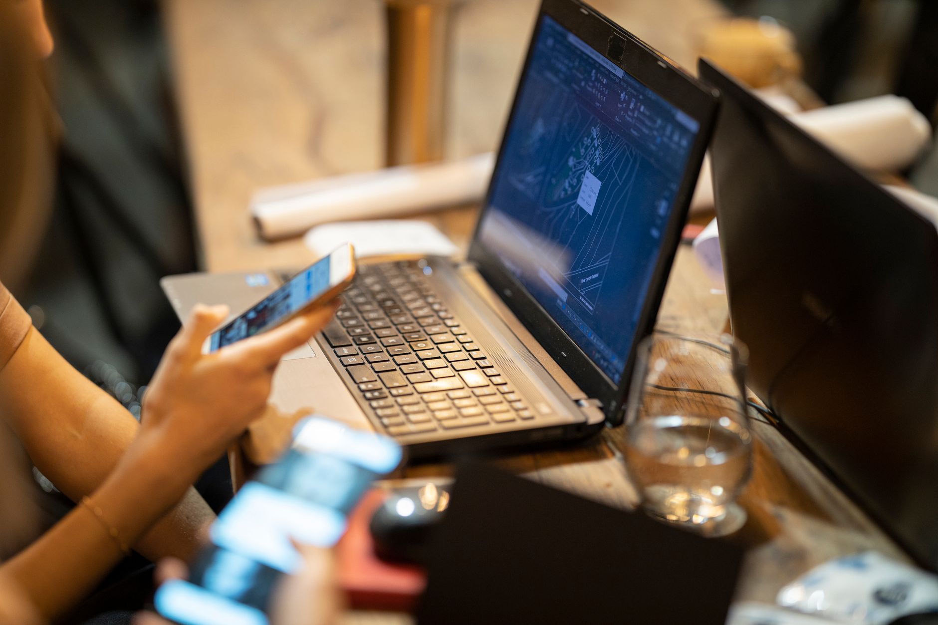 a worried person watching a laptop screen with remote support software open while holding a phone