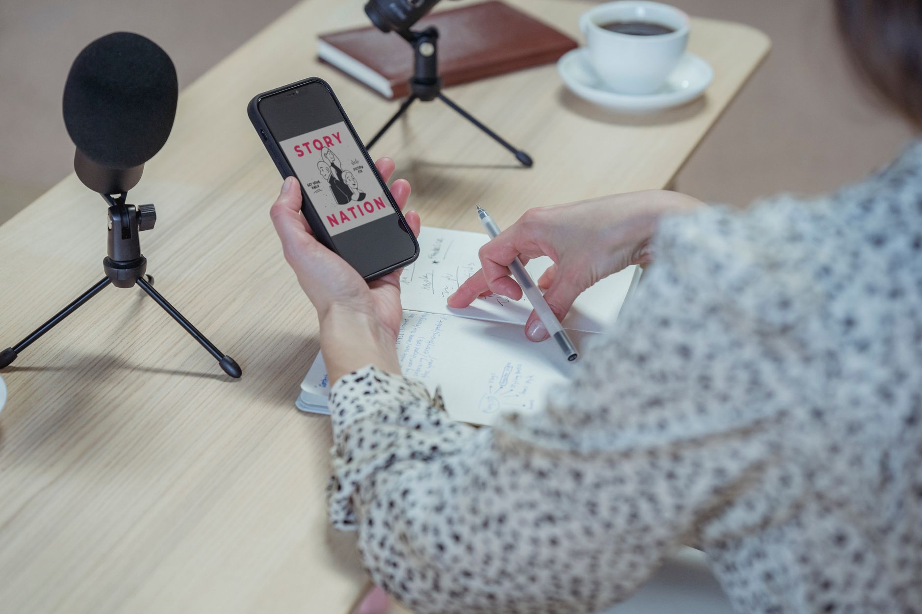 A person records a voice note on a smartphone in a bright living room while another phone sits on the table.