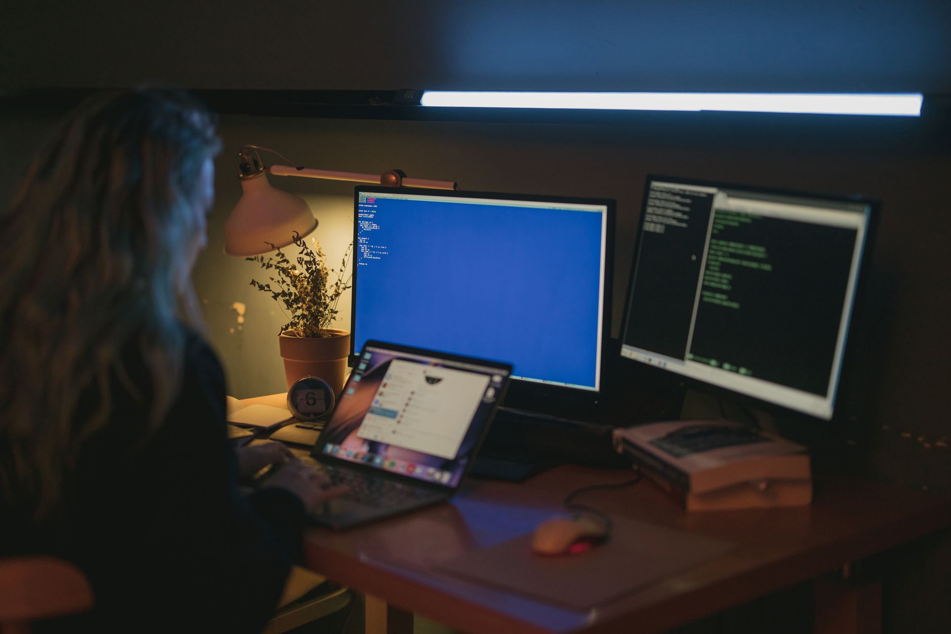 A fraud investigator reviews deepfake video frames on a monitor showing two faces that look similar.