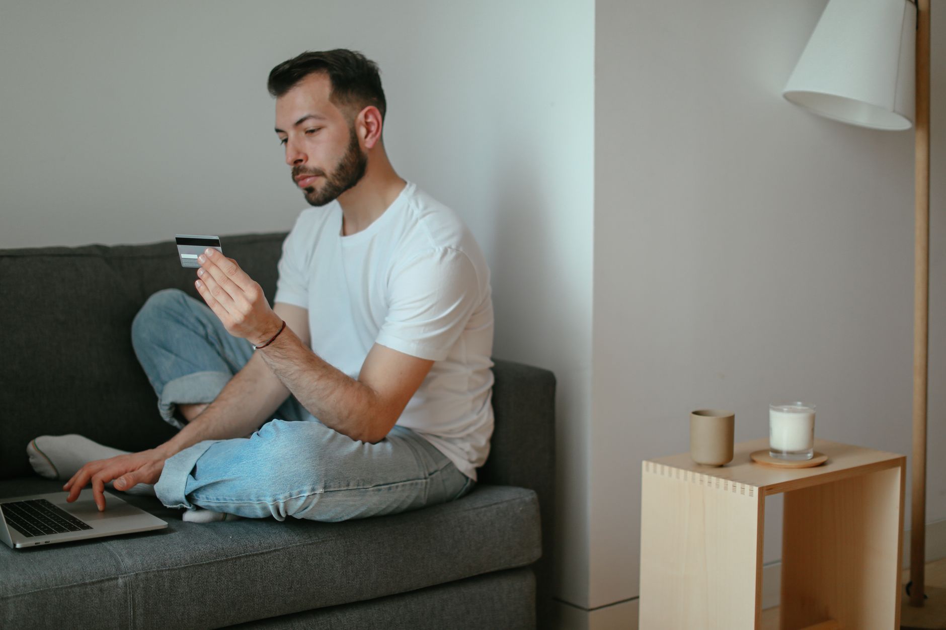 A person reviews a credit card statement on a laptop with a worried expression